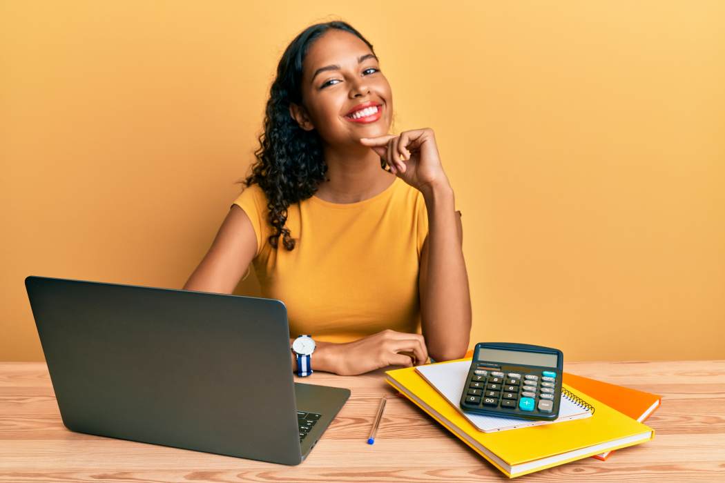 Female learner with laptop and calculator against colourful orange background