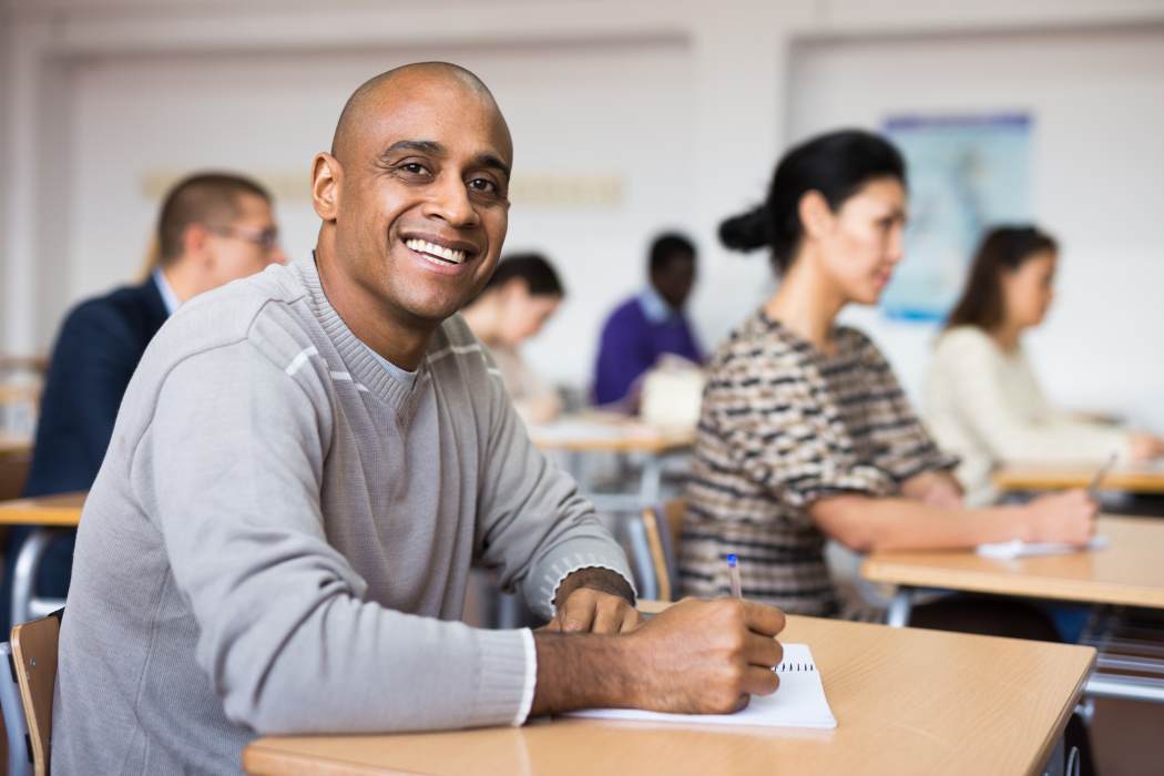 Smiling man taking part in a class in a college setting 
