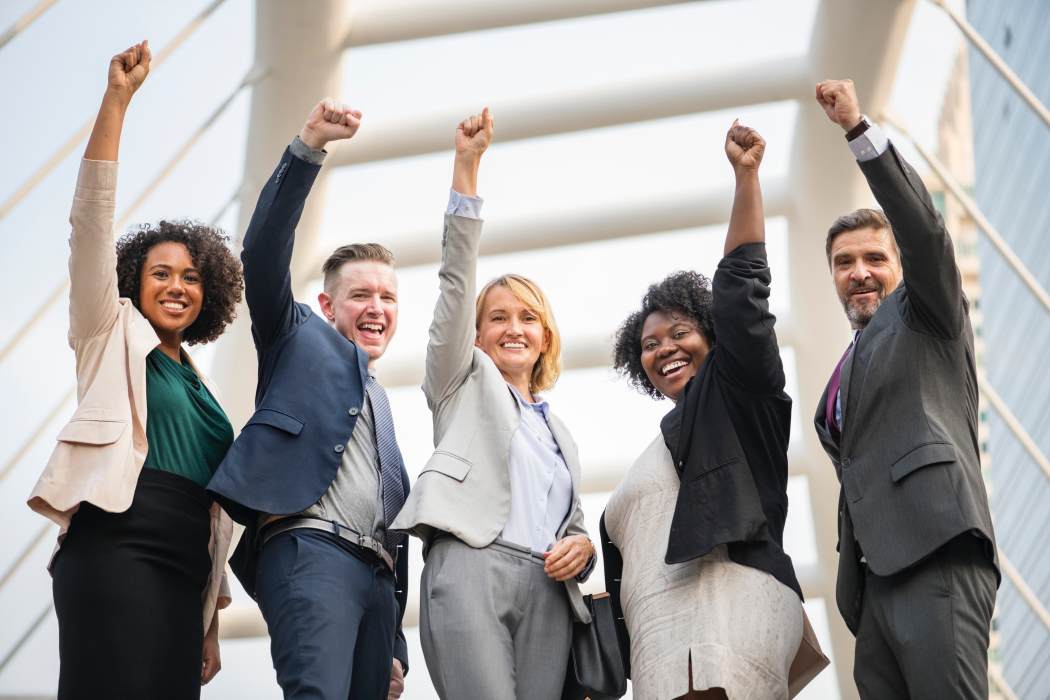 image of businesspeople in suits with hands raised in success