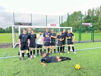 Our young people's football team posing in front of a goal